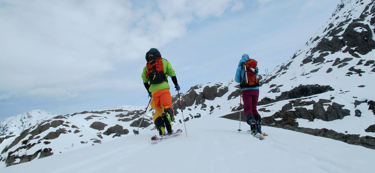 Rino R. Berg og Ida Sollie er på vei over demningen. Målet er Bukkanuten. Anmarsjen blir litt lengre når man er ivrigere enn snøsmeltingen. Foto: Trygve Studsvik