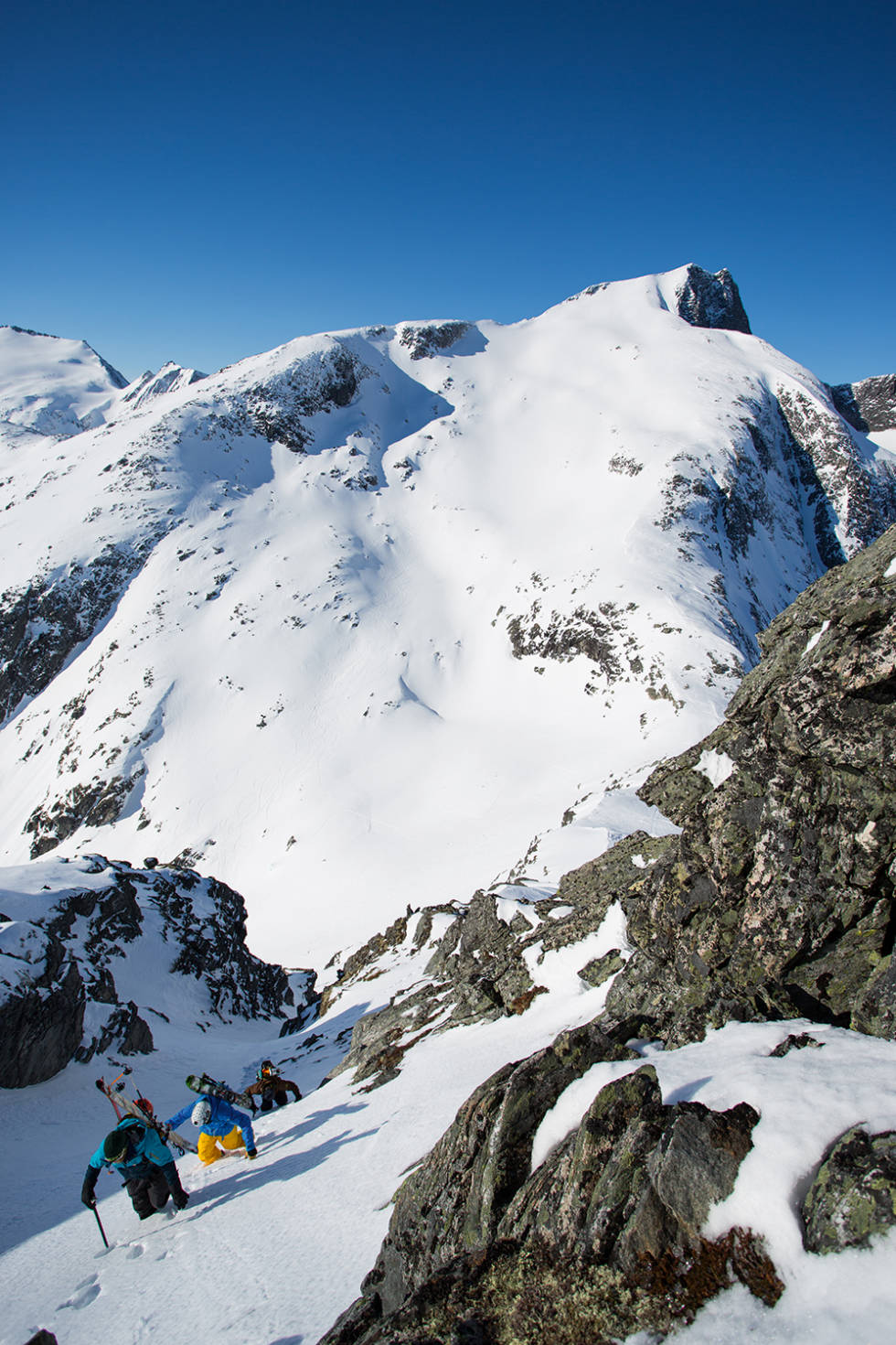 PÅ VEI OPP: Det fins flere ruter på vei opp til Glennfjellet. En av dem er denne korte renna, som har en bonus i from av utsikt til det deiligste skiterrenget på Litlskjorta i bakgrun- nen. Tor Olav Naalsund, Asbjørn Eggebø Næss og Trond Finseth er på vei opp. Foto: Tore Meirik Glennfjellet