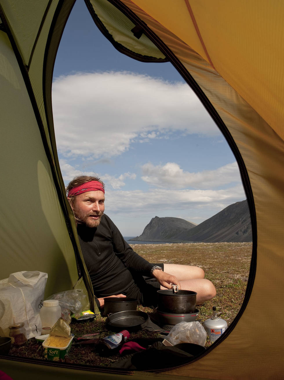 Uteliv: Enkelte sommermorgener er det godt å trekke ut i friluft. Mann i teltåpning på fjellet