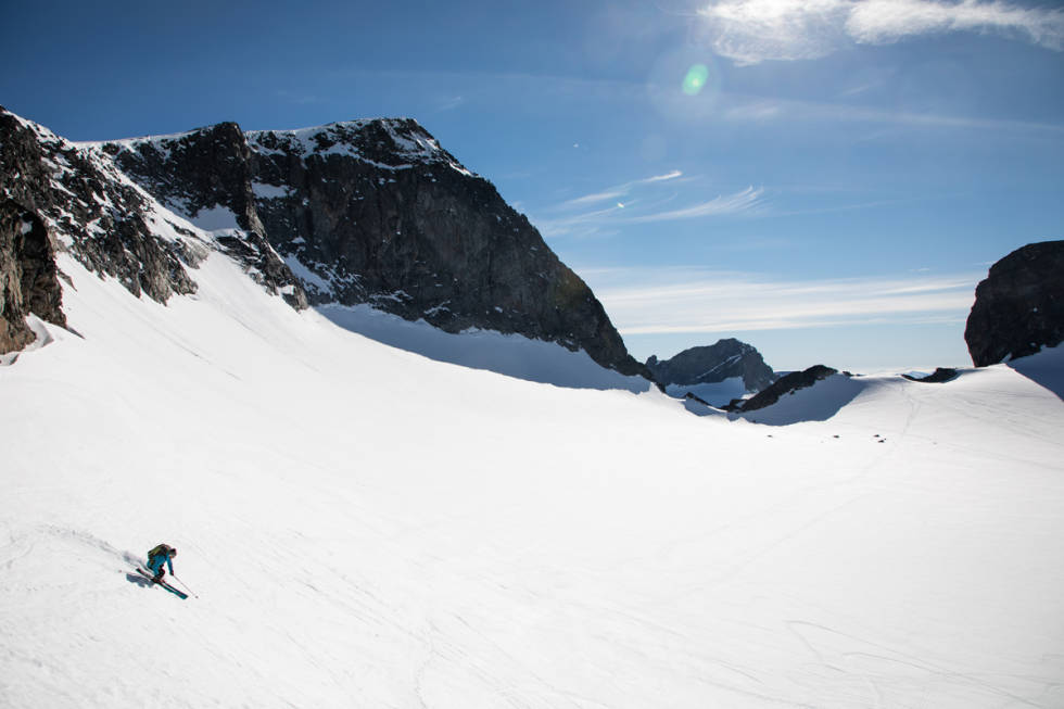 GALDHØPIGGEN: Erlend Sande setter en fin sving på sin sommersnø med Galdhøpiggen i bakgrunnen. Foto: Tore Meirik Galdhøpiggen sommerskisenter Juvass