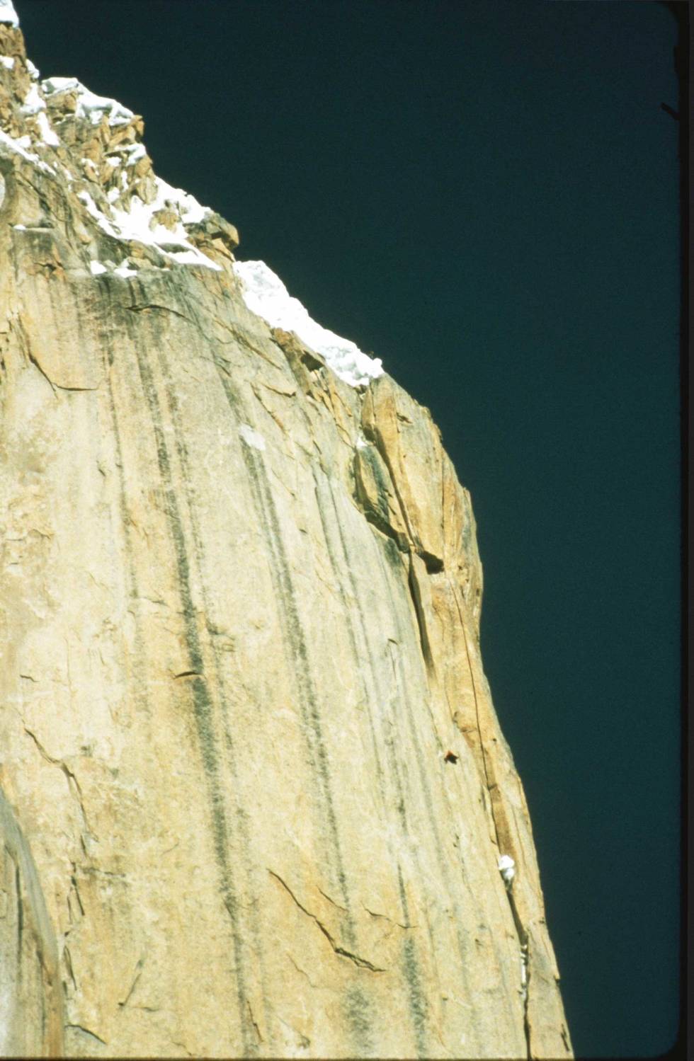 Topper ut: Norskeruta på Trango er et faktum. Nederst på snøfeltet skimtes en person i silhuett mot himmelen. Den svarte trekanten nede i veggen under er hengeteltet. Foto: Stein P. Aasheim Great-Trango-klatring-4