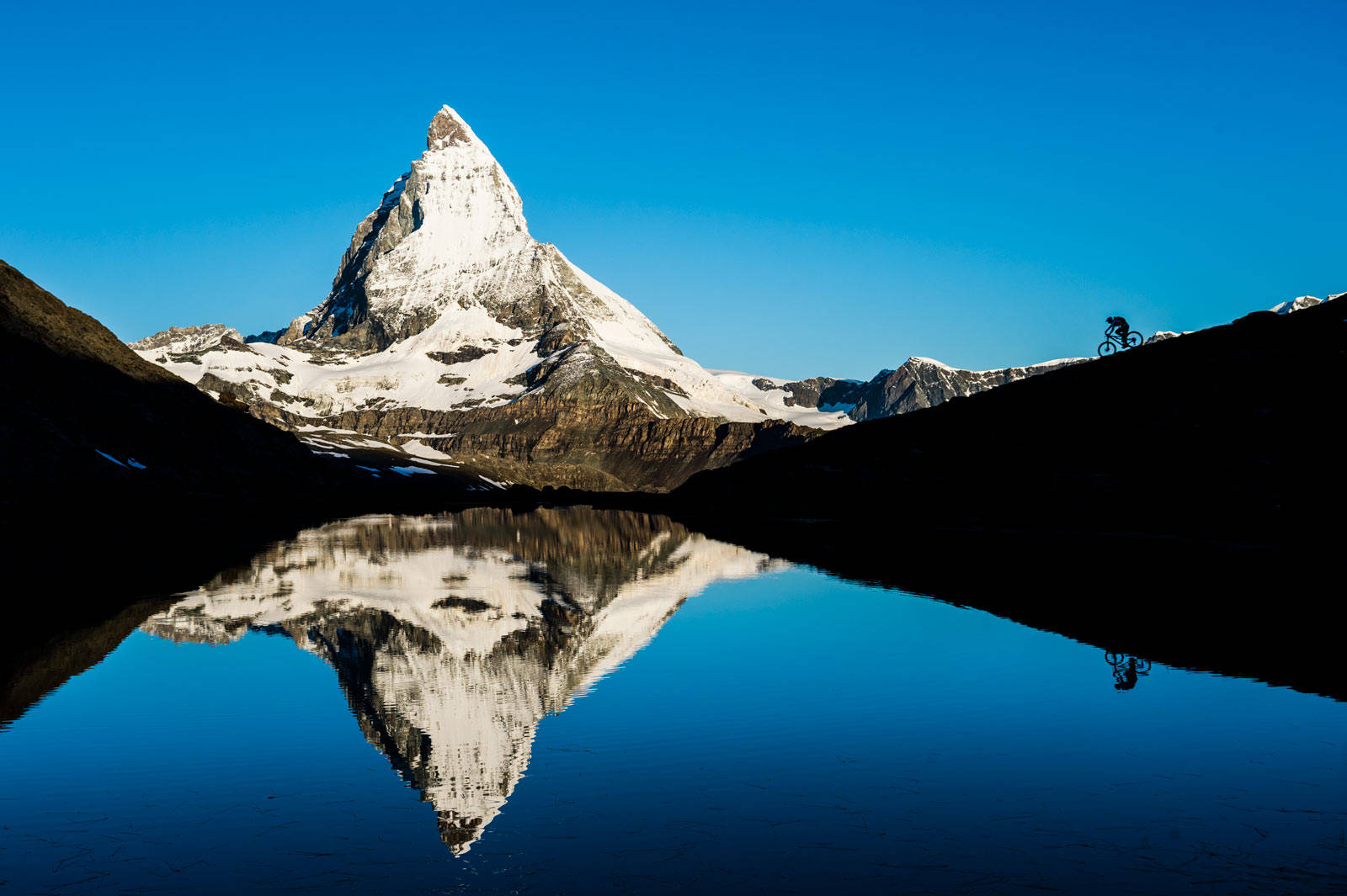 Postkort: Soloppgang ved Riffelsee, høyt over Zermatt, en tidlig august-morgen. Det ikoniske fjellet Matterhorn, og Elle Cochrane speiler seg i det stille vannet. Guide-til-stisykling-i-Alpene-9