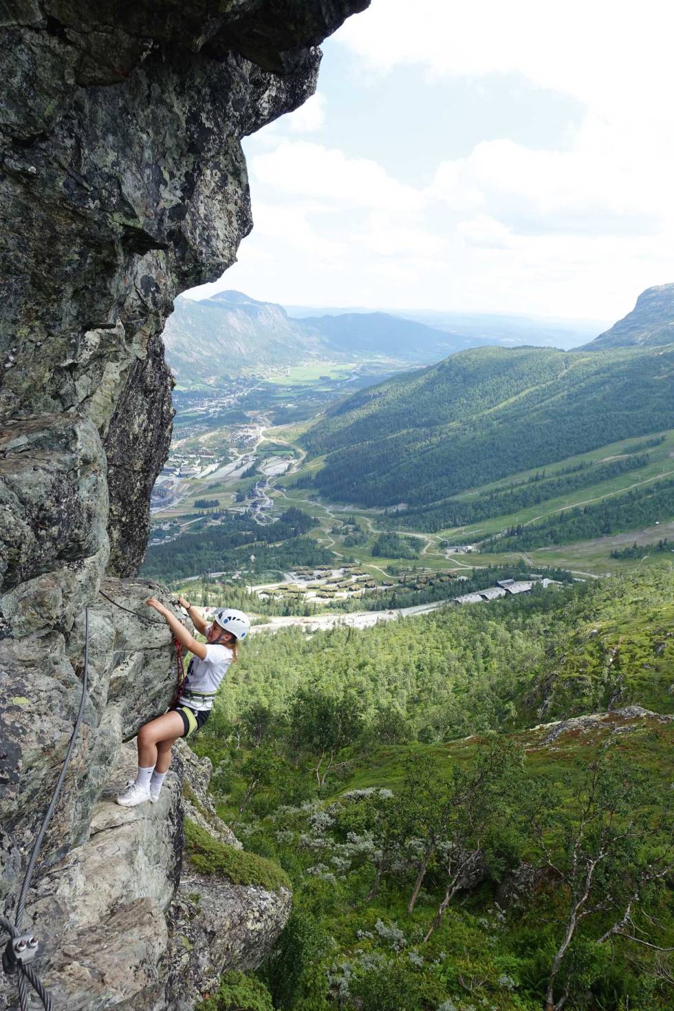 LUFTIG: Maria Wassdahl Meirik holder seg fast i fjellet med jernstigen høyt over skisenteret i Hemsedal. Sentrum ses i bakgrunnen. Bilde: Tore Meirik Hemsedal-via-ferrata