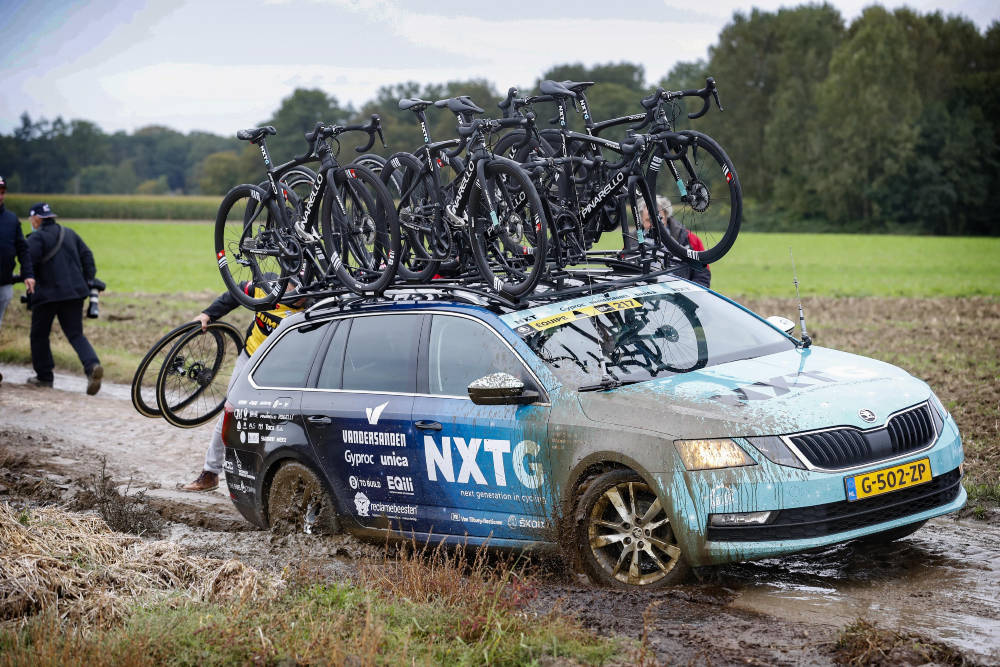 TRØBBEL: Ikke bare rytterne strevet i gjørma. Her har en bil satt seg fast og en Jumbo-Visma-soigneur forsøker å hjelpe bilføreren ut av gjørma. paris-roubaix femmes (17)