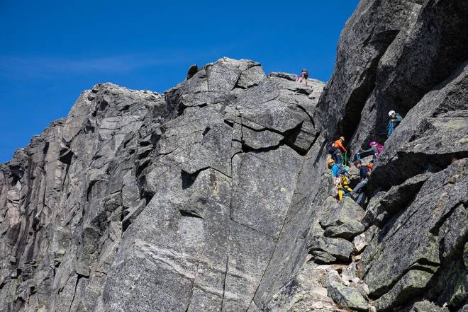 Klatrere venter på tur ved De ti forbitrede fingertak – hvis førstebestigning fyller 110 år i år. Selve fjellet er for øvrig 1,8 milliarder år gammelt. Foto: Tore Meirik Klatring Stetind