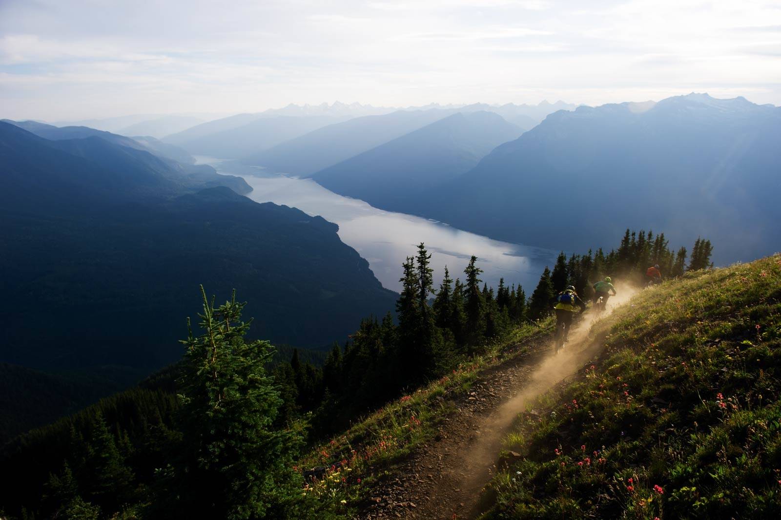 Inn i soloppgangen: Linden Feniak, Kris Mcmechan og Evan Schwartz blåser støvet av en episk sti ned fra toppen av Idaho Peak, en drøy times kjøring fra Nelson. Ved foten av fjellet ligger Slocan Lake. Stisykling-guide-British-Columbia-2