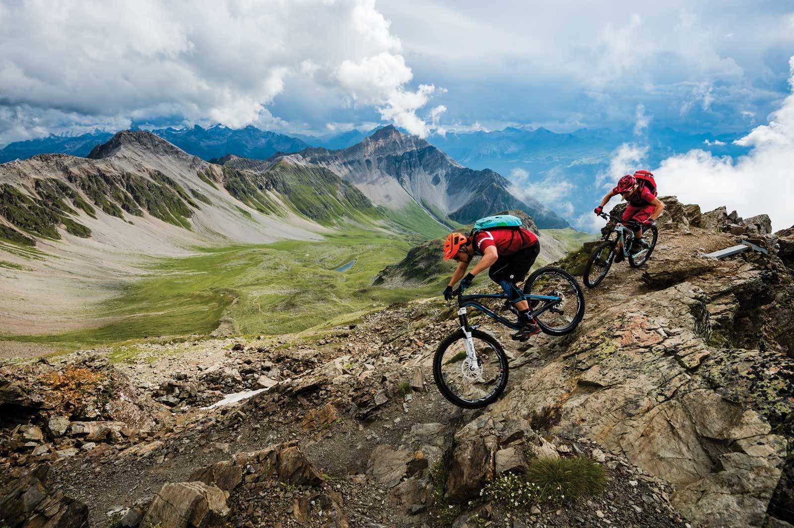 PÅ KANTEN: Fra Parpaner Rothorn (2861 moh), er utsikten imponerende, og stisyklingen fantastisk. Tobias Woggon og Julia Hoffman setter i gang fra toppryggen med fjellene i Bernina-kjeden langt borte i horisonten. Stisykling-i-sveits-Lenzerheide-2