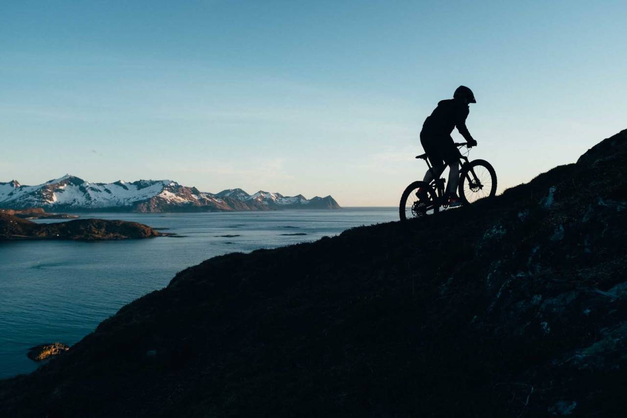 YTE, SÅ NYTE: Torgrim Sollid jobber seg opp ett av de få syklebare partiene til Hillesøytoppen før sykkelen må bæres igjen. Mens Senja bader i sol rett før klokken bikker midnatt. stisykling tromsø yttersia