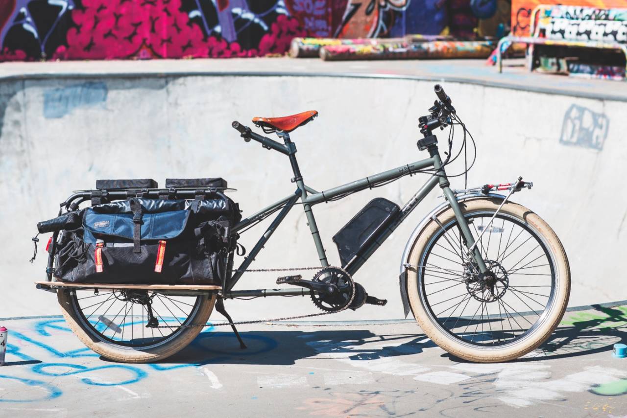 VÅR EGEN: Dette er familiens stasjonsvogn på to hjul: En Surly Big Dummy longtailsykkel med ettermontert Bafang BBS-01 elmotor og eget styre til junior bakpå, der det er god plass til to store barn. Sykkelen kommer levert med to digre sidevesker, som kan utvides til å holde selv store pappesker på plass. En 90-liters North Face duffelbag går lett inn på hver side, og da er det fortsatt plass til én til oppå lasteplanet. En utrolig morsom og kapabel sykkel både til turbruk og som hverdagstransportør, og vår klare kandidat til tittelen Den Perfekte Hverdagssykkel. Foto: Geir Anders Rybakken Ørslien transportsykkel