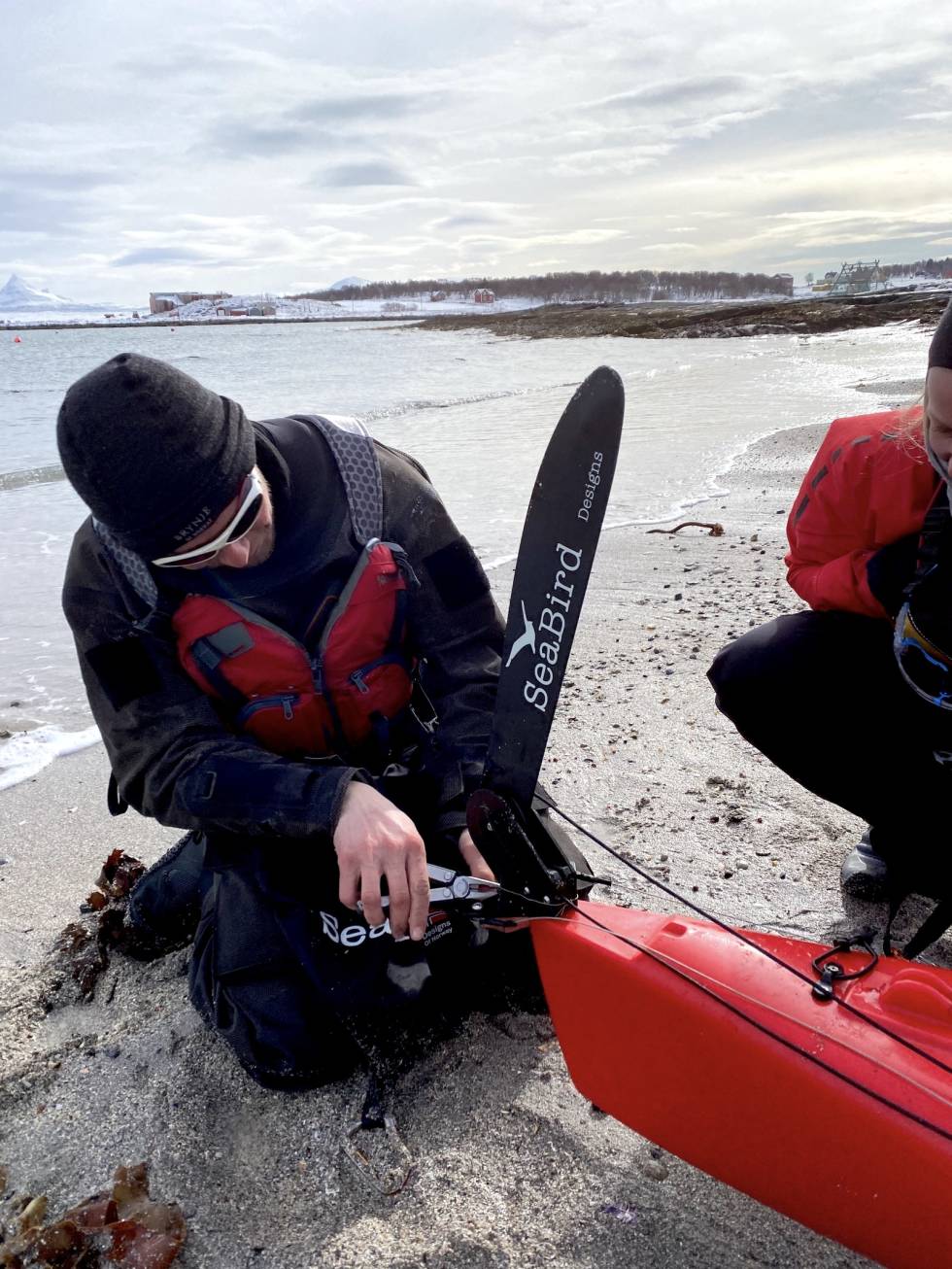REPARERING: Mekking av ror på Sandsøya. Roret til Mina falt av mellom Senja til Hinnøya. Vi måtte reparere det med noe streng og svivler fra fiskekroker. Heldigvis er Øystein flymekaniker og turens Mac-Gyver. Foto: Tor Wigum fikse ødelagt turutstyr